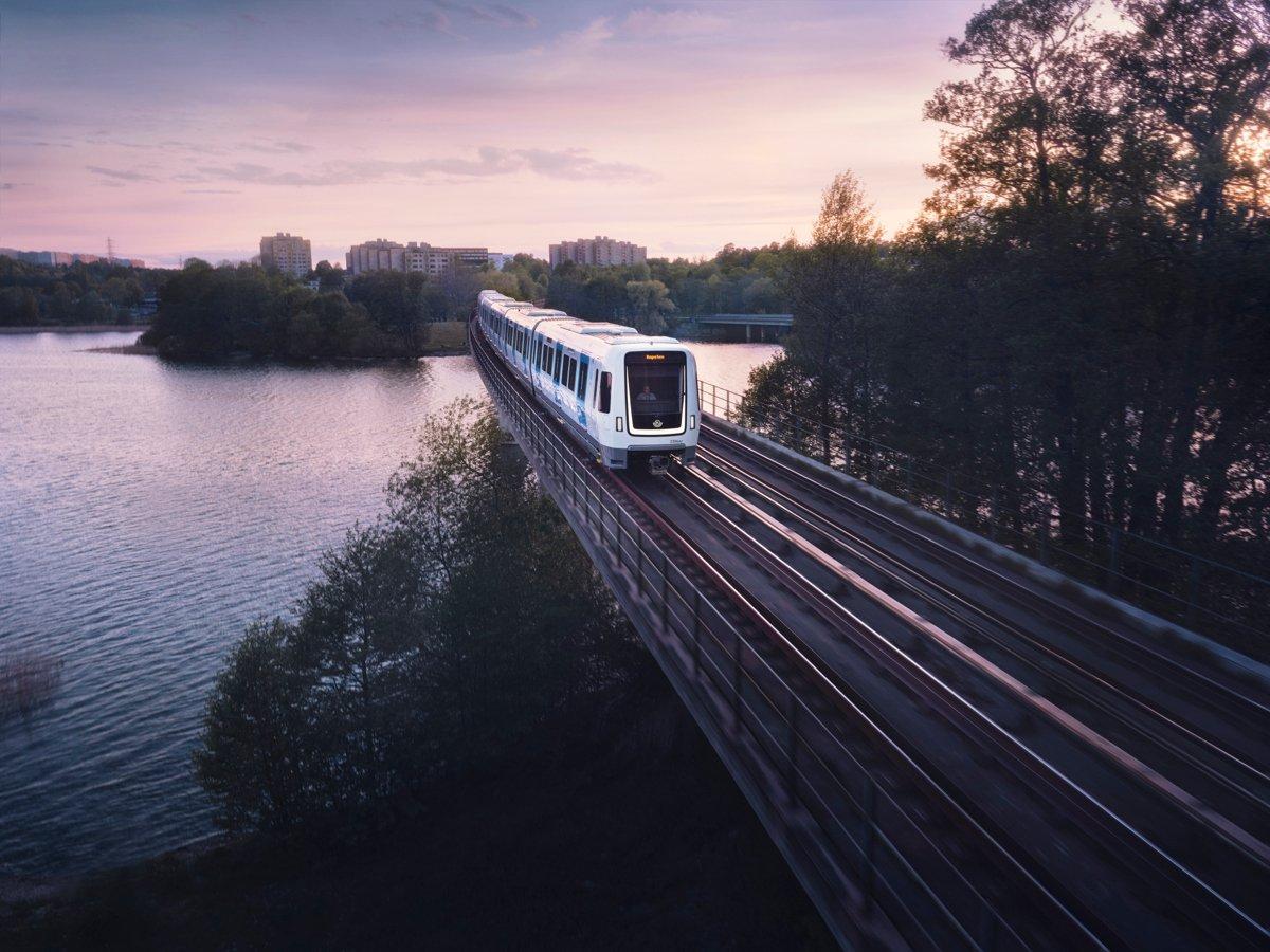 Foto på en tunnelbana som kör över en bro. På bilden syns vatten och träd. 